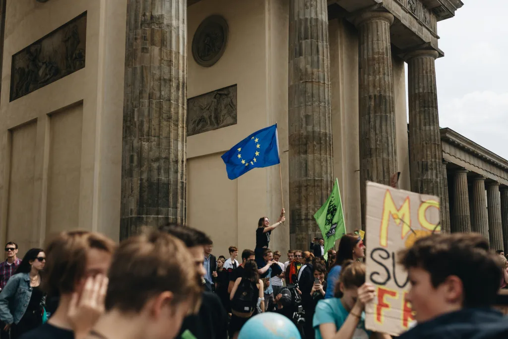 Crowd protesting in front of Bradenburg Gate in Berlin, Germany. A young crowd with an European Union flag being waved in the center.