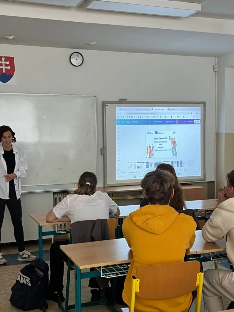 Students sitting at the desk listening to the workshop trainer, back perspective with presentation being projected in front.