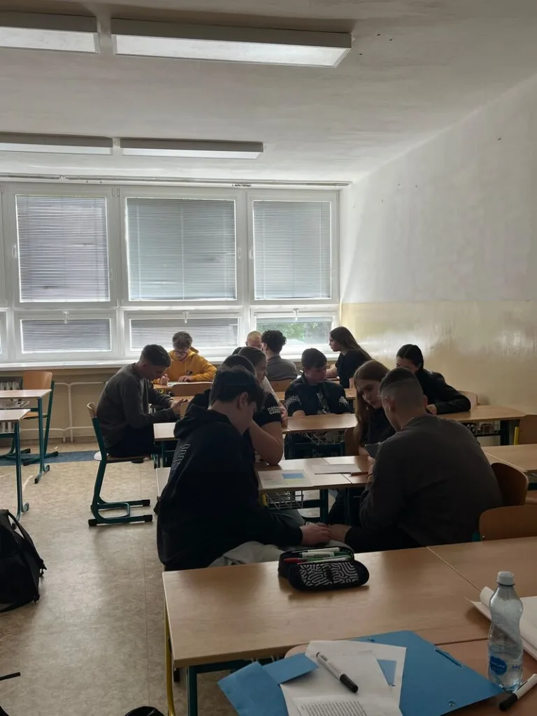Students working in groups, sitting around desks.