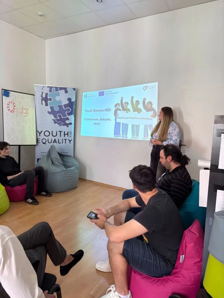 Alternate view of sitting workshop participants listening to trainer, with slide presentation being projected in front.