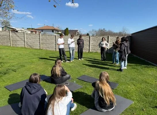 Outdoor activity. Seven participants standing and four sitting on a grass lawn.