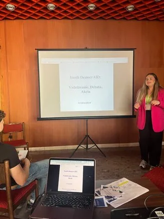 Workshop trainer standing next a projector screen with and audience member in front.