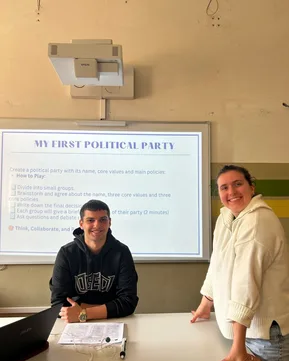 Two workshop participants posing for the photo in front of a projection of a slide presentation.
