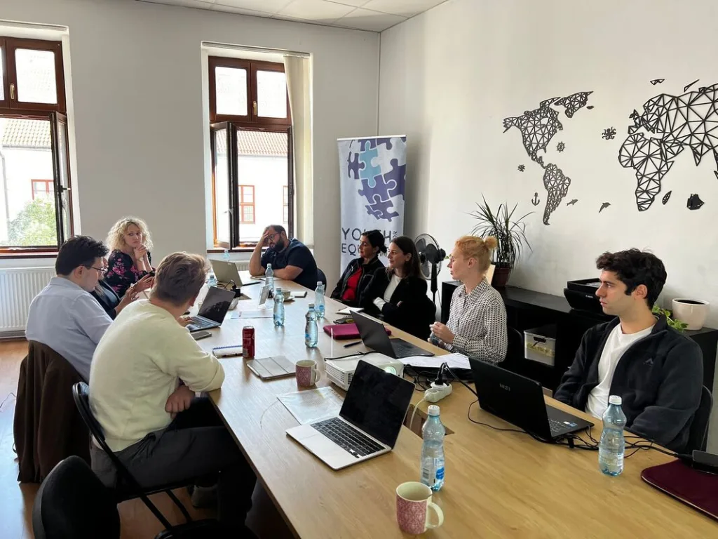 Nine trainers sitting around a table during a meeting.